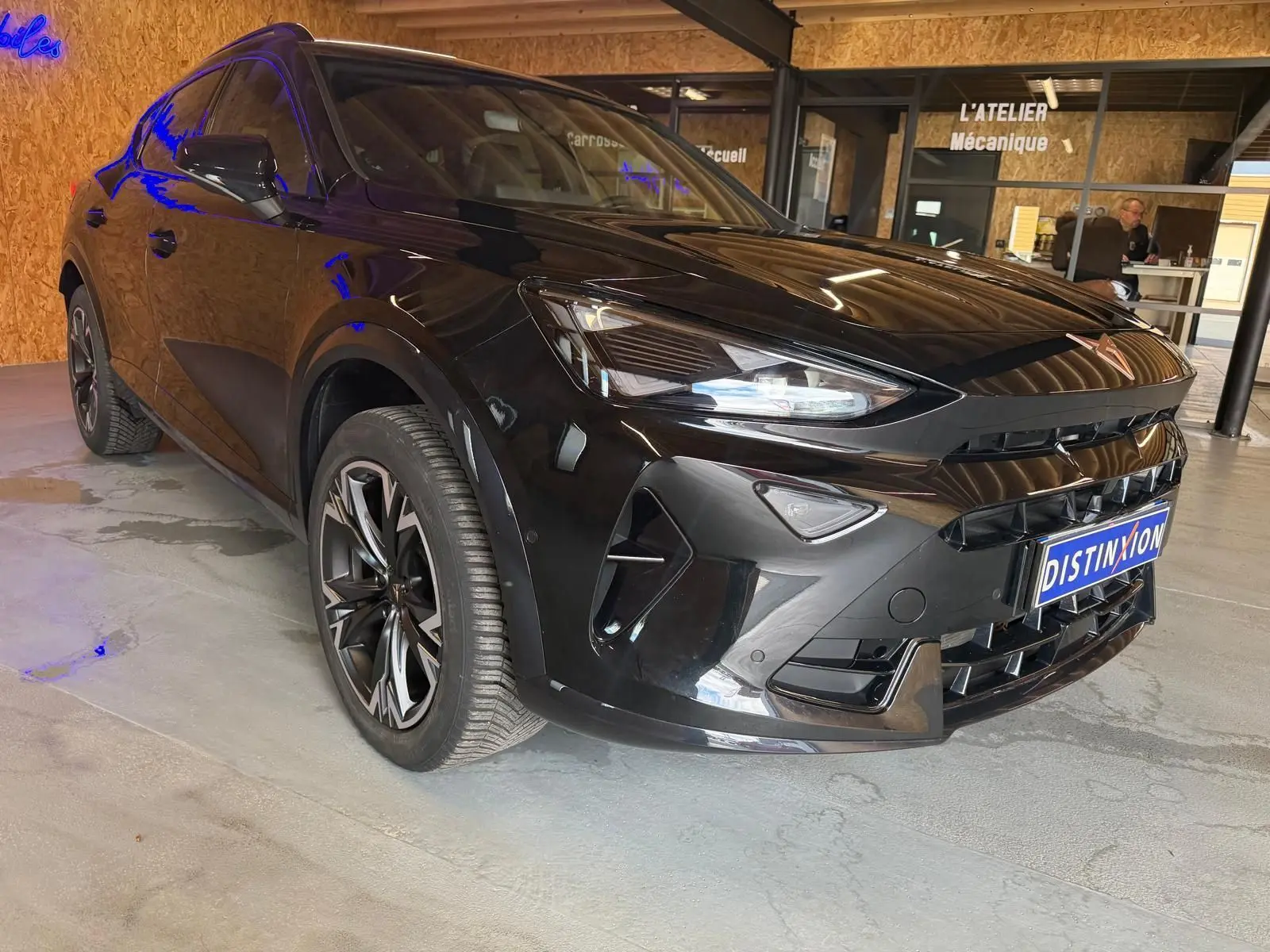 Vue 3/4 avant gauche d'un CUPRA Formentor noir 2025 avec jantes alliage et calandre distinctive en intérieur showroom.
