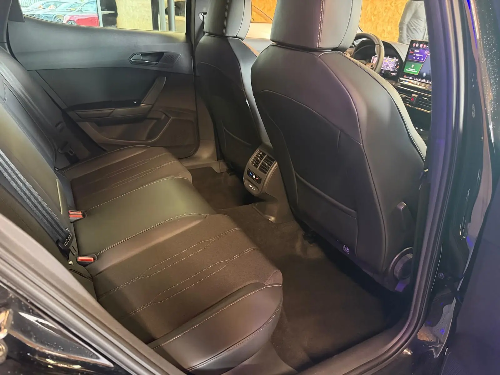 Vue intérieure arrière droite du CUPRA Formentor noir 2025, sièges cuir noirs et console centrale avec commandes climatisation.