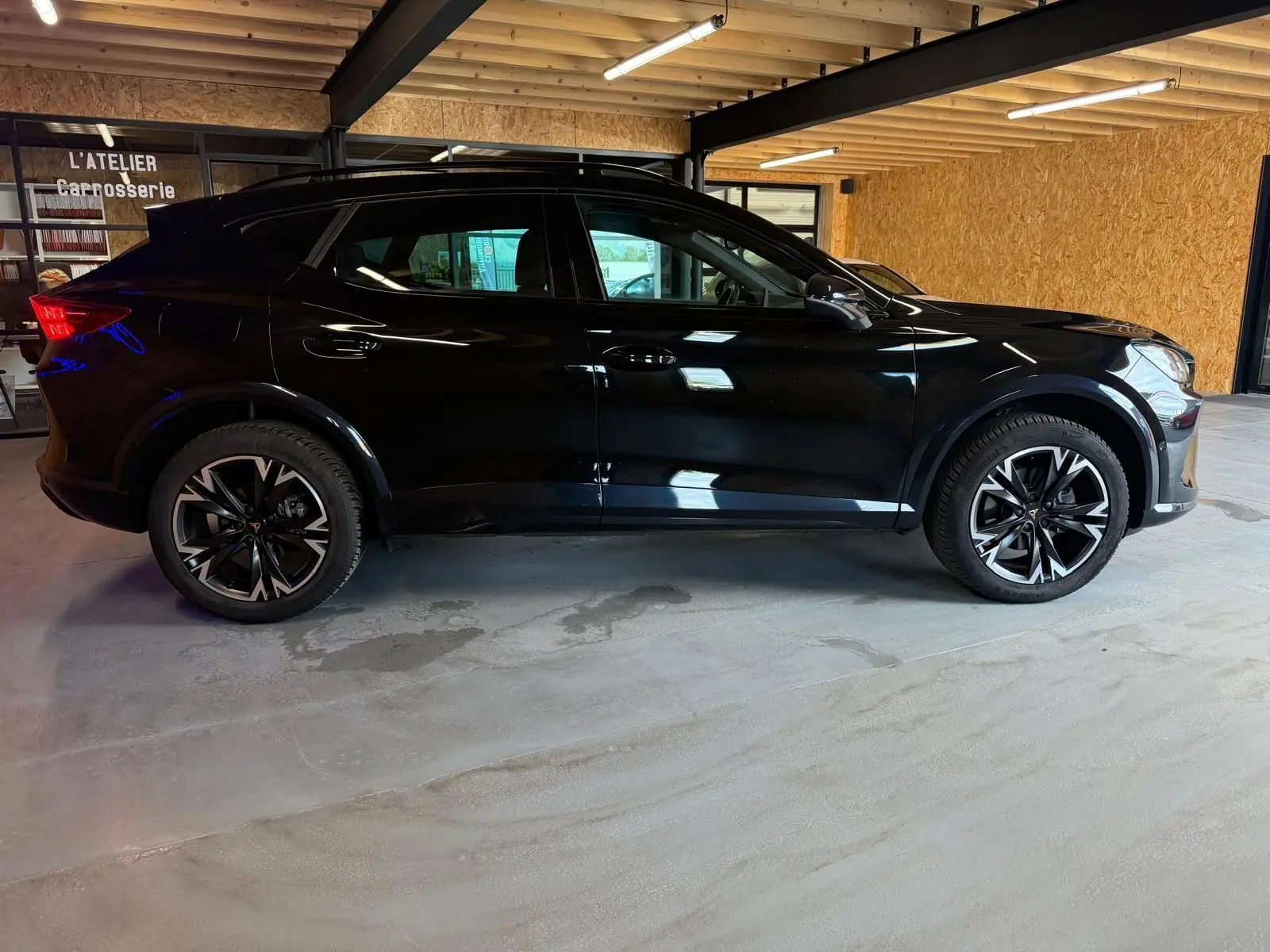 Vue de profil côté gauche du CUPRA Formentor noir 2025 avec jantes alliage 18'' et rétroviseurs rabattables électriques.