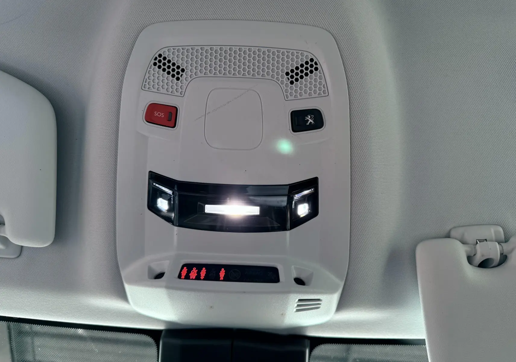Vue en gros plan du plafonnier intérieur gris clair avec boutons SOS et logo Peugeot éclairés sur Peugeot 308 SW noir.