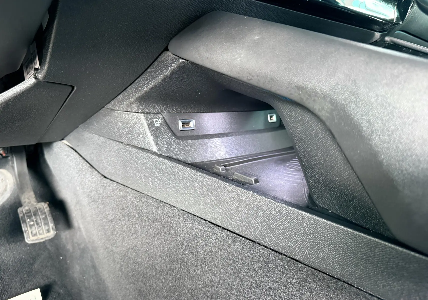 Prise USB et compartiment de rangement côté gauche sous le tableau de bord d'une Peugeot 308 SW noir métal.