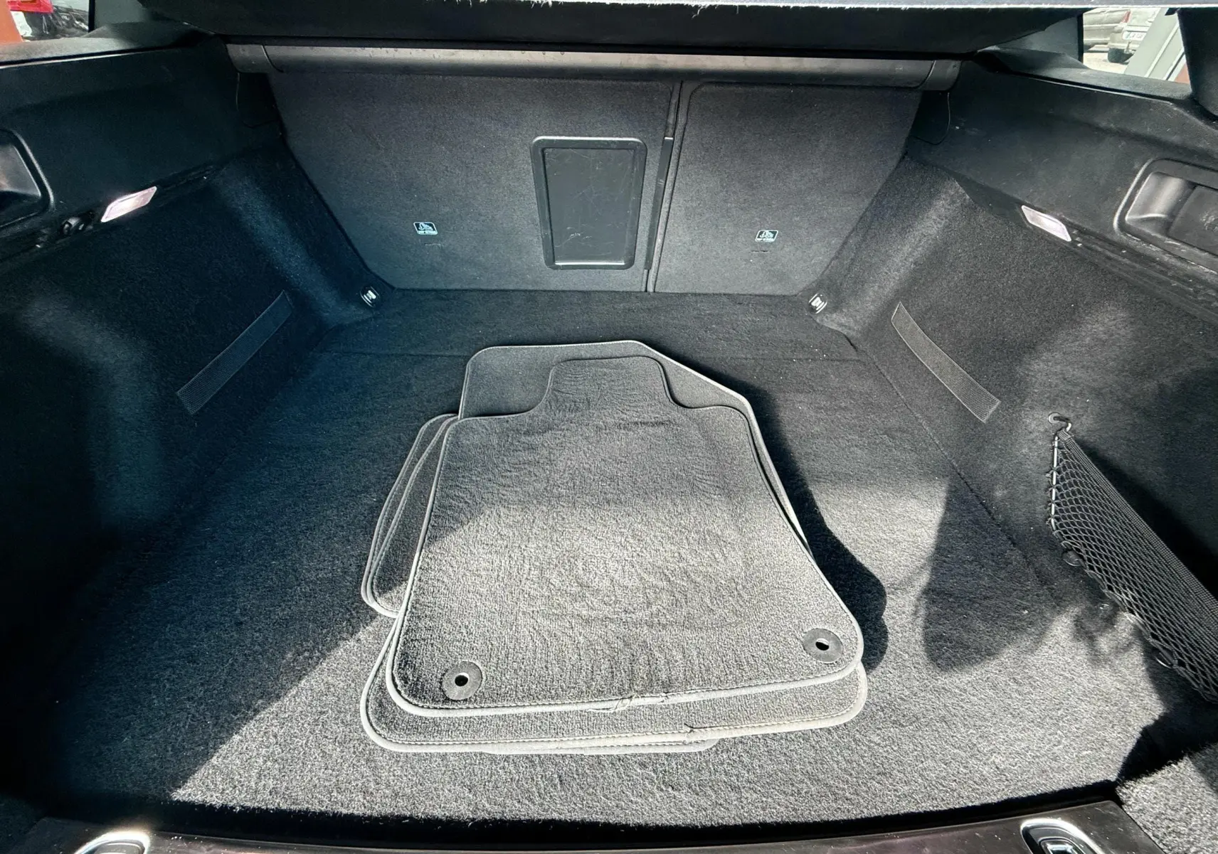 Coffre spacieux de Peugeot 308 SW noir métal, vue intérieure avec tapis de sol gris posés au centre.