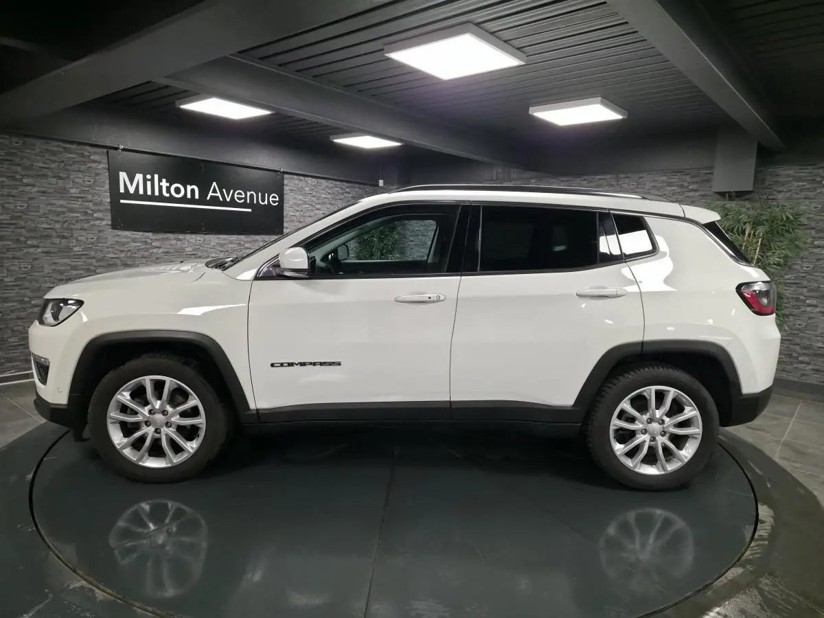 Jeep Compass blanc en profil côté gauche, avec jantes alliage 18 pouces et vitres arrière surteintées.