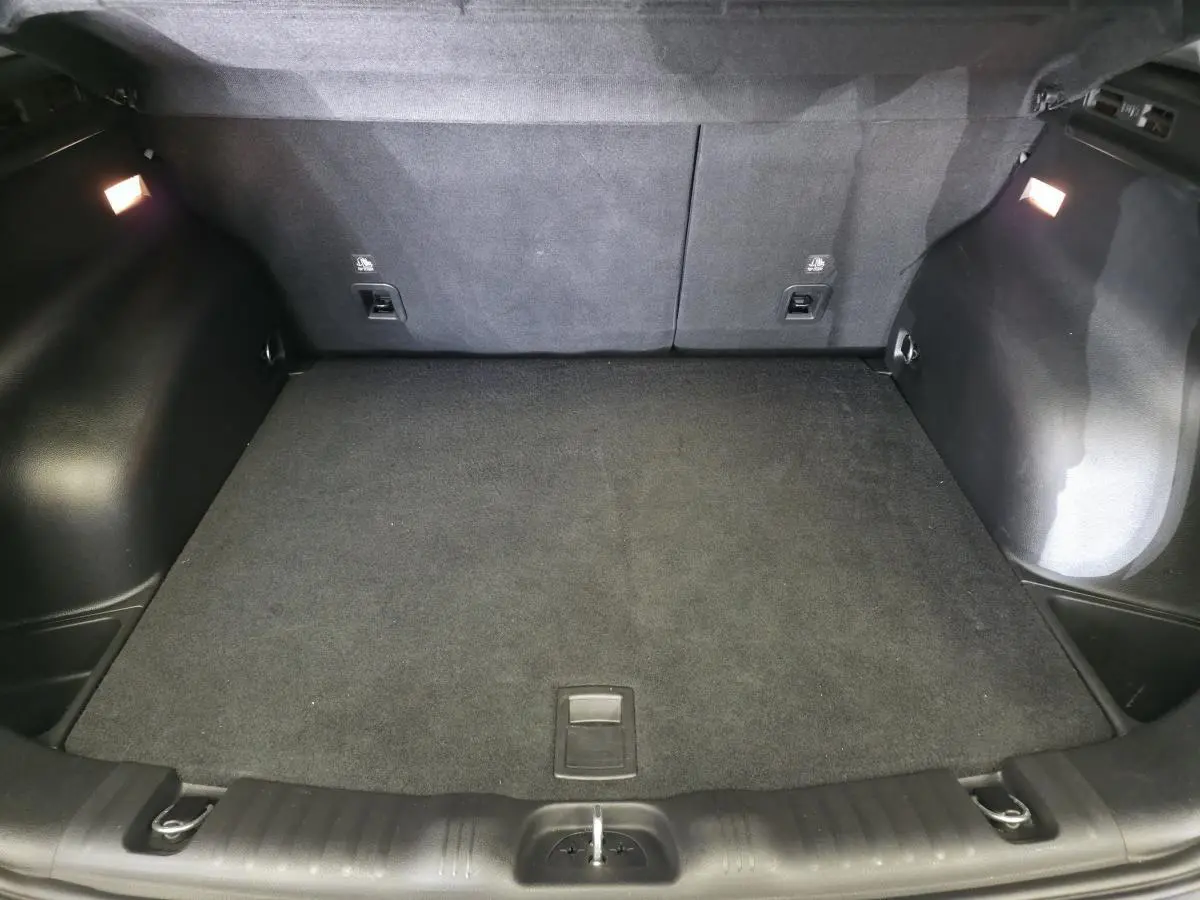 Coffre spacieux du Jeep Compass blanc 2020, vue intérieure arrière avec tapis de sol noir et éclairage intégré.