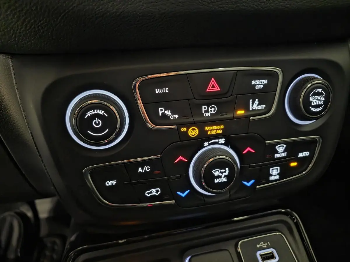 Panneau de commande central noir avec boutons lumineux de climatisation et audio dans un Jeep Compass blanc de 2020.