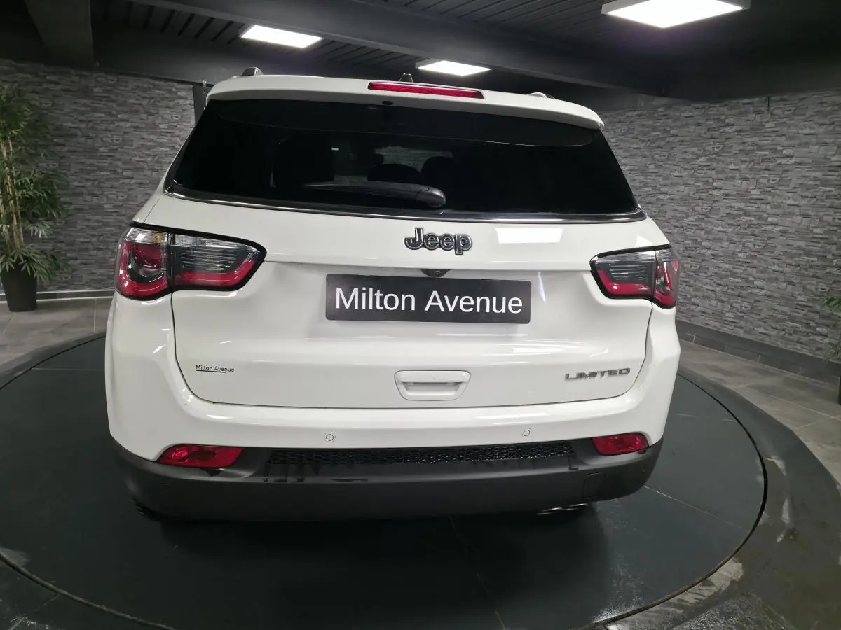 Vue arrière d'un Jeep Compass blanc Limited 2020 avec vitres arrière surteintées et logo distinctif sur le hayon.