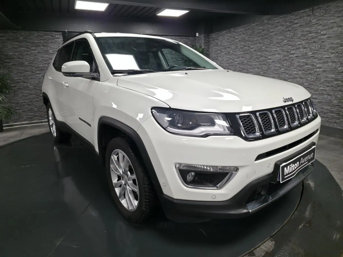 Jeep Compass blanc en 3/4 avant droit, avec jantes alliage 18 pouces et calandre distinctive à sept fentes.