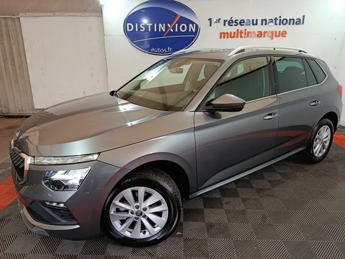 Vue 3/4 avant droit d'un Skoda Kamiq gris clair avec phares LED et jantes alliage dans un showroom.