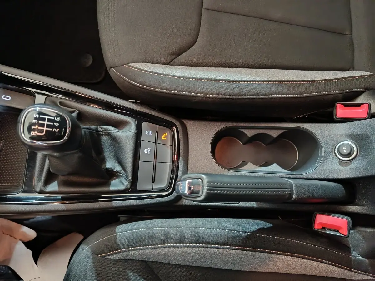 Vue plongeante sur la console centrale du Skoda Kamiq gris clair, avec levier de vitesse manuel et frein à main en cuir.