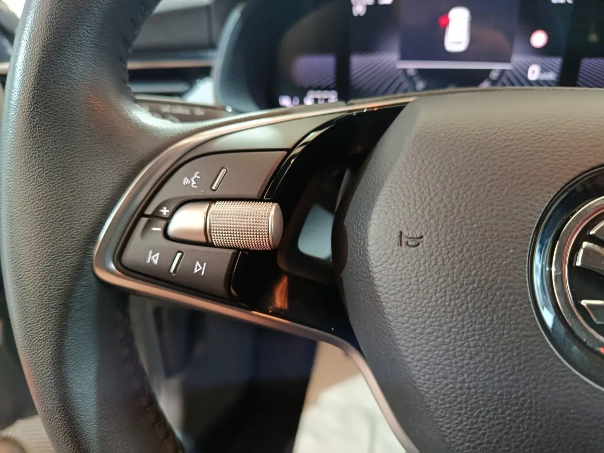 Gros plan sur le volant cuir noir du Skoda Kamiq 2024, avec commandes multifonctions et molette argentée.