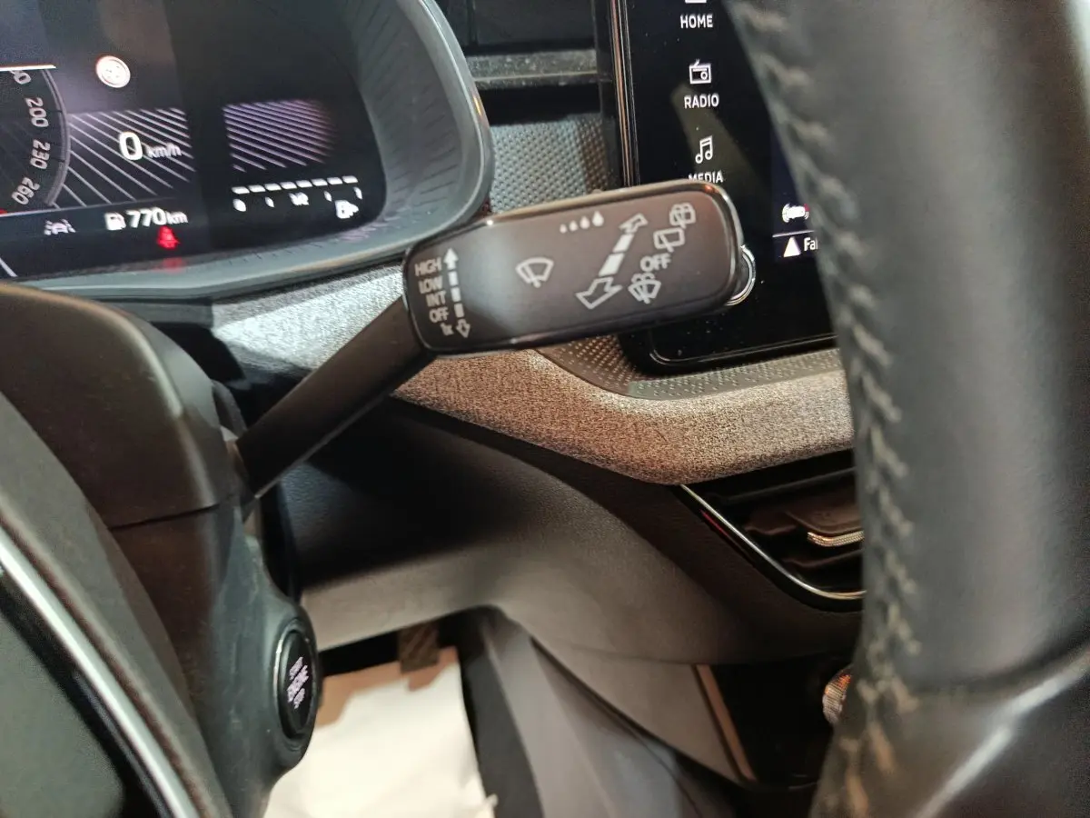 Gros plan sur la manette d'essuie-glace à gauche du volant cuir dans l'habitacle du Skoda Kamiq gris clair 2024.