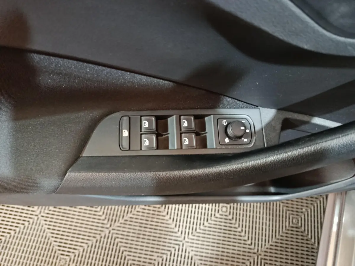 Gros plan sur les commandes de lève-vitres et réglage des rétroviseurs côté conducteur du Skoda Kamiq gris clair 2024.