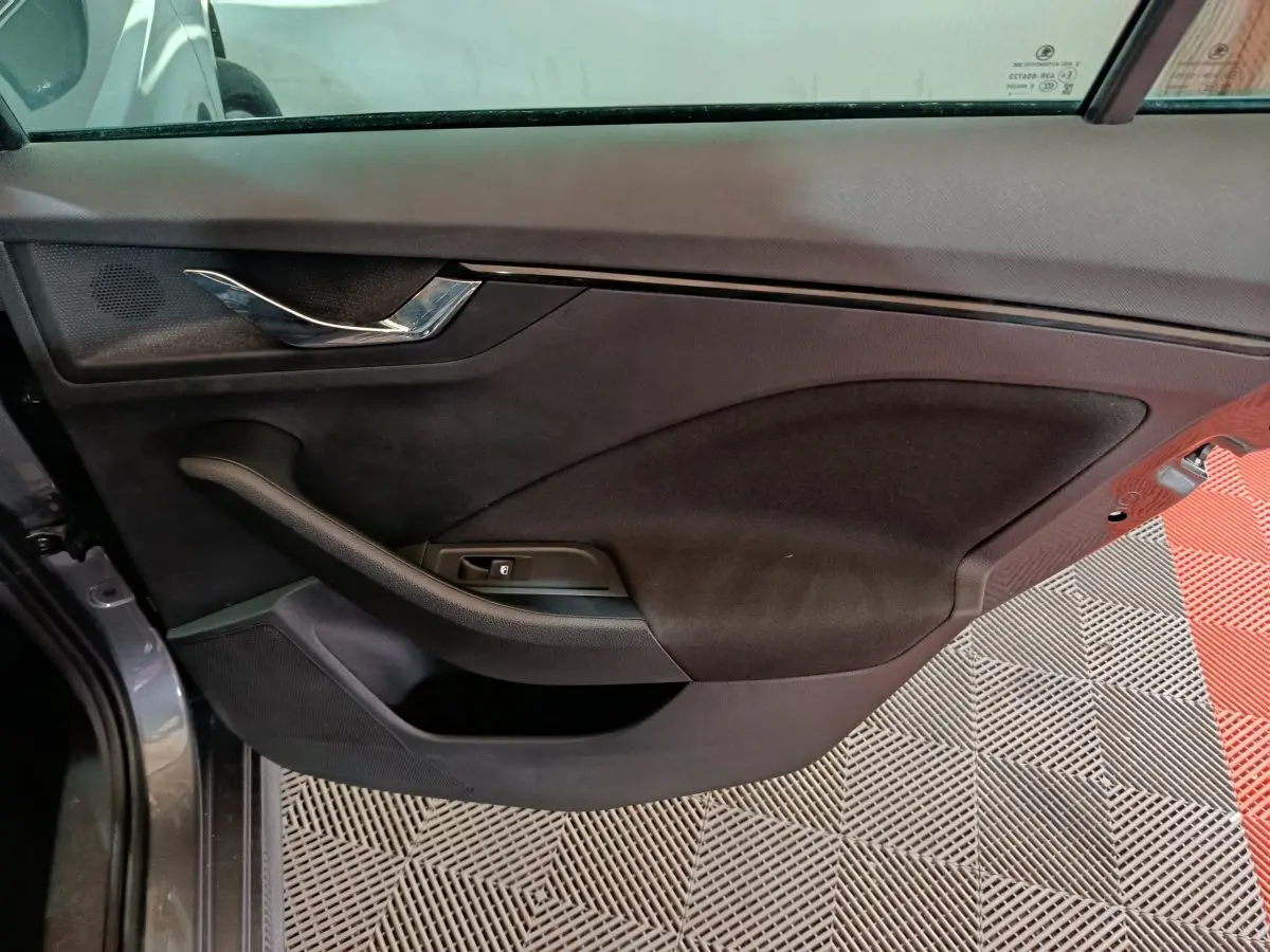 Vue intérieure côté gauche de la porte avant gris clair du Skoda Kamiq 2024 avec poignée chrome et commande de vitre.