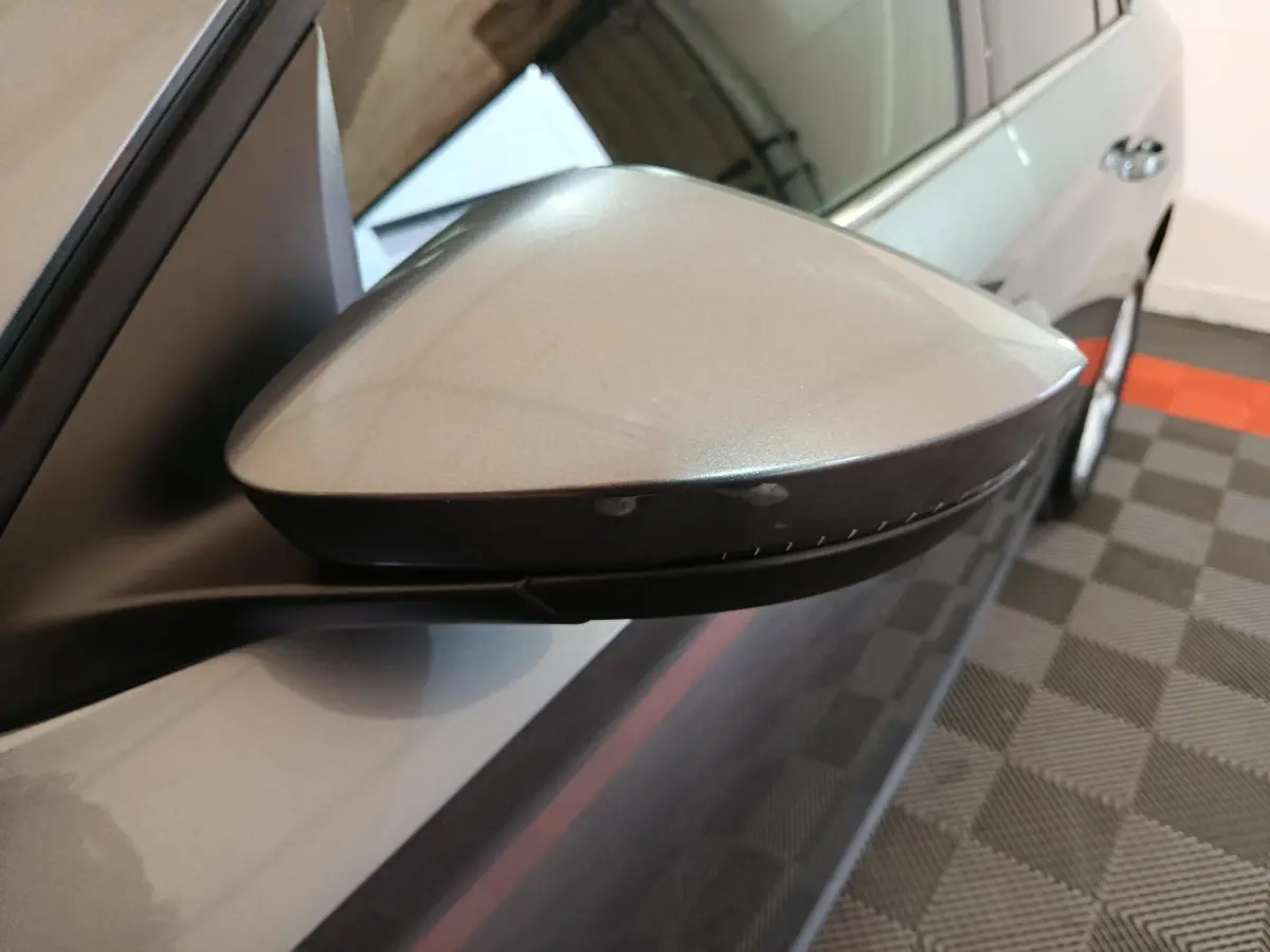 Gros plan sur le rétroviseur droit gris clair du Skoda Kamiq 2024, avec clignotant intégré et carrosserie visible.