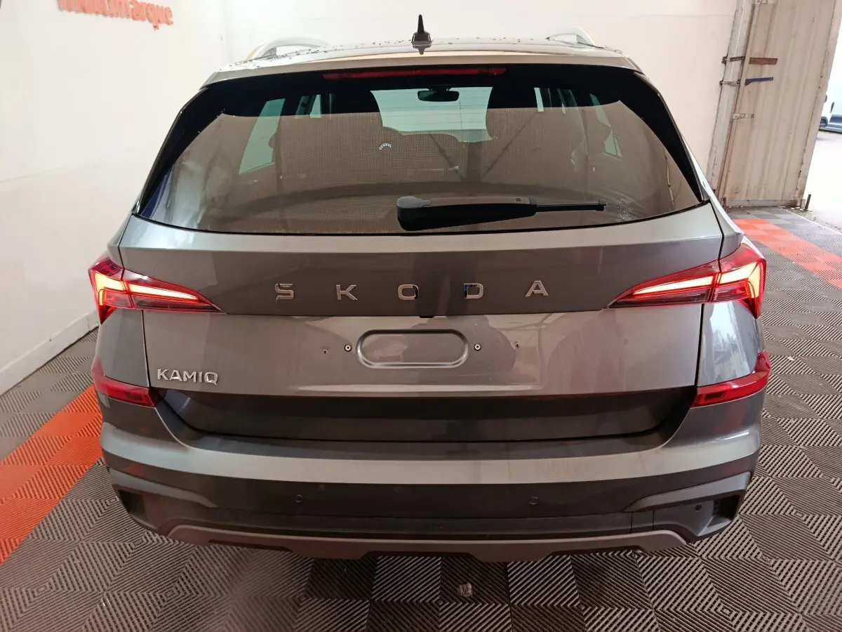 Vue arrière d'un Skoda Kamiq gris clair avec feux LED allumés et logo SKODA bien visible.