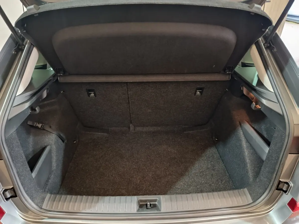 Coffre ouvert vu de l'arrière du Skoda Kamiq gris clair 2024, espace de chargement vide et tapis gris.