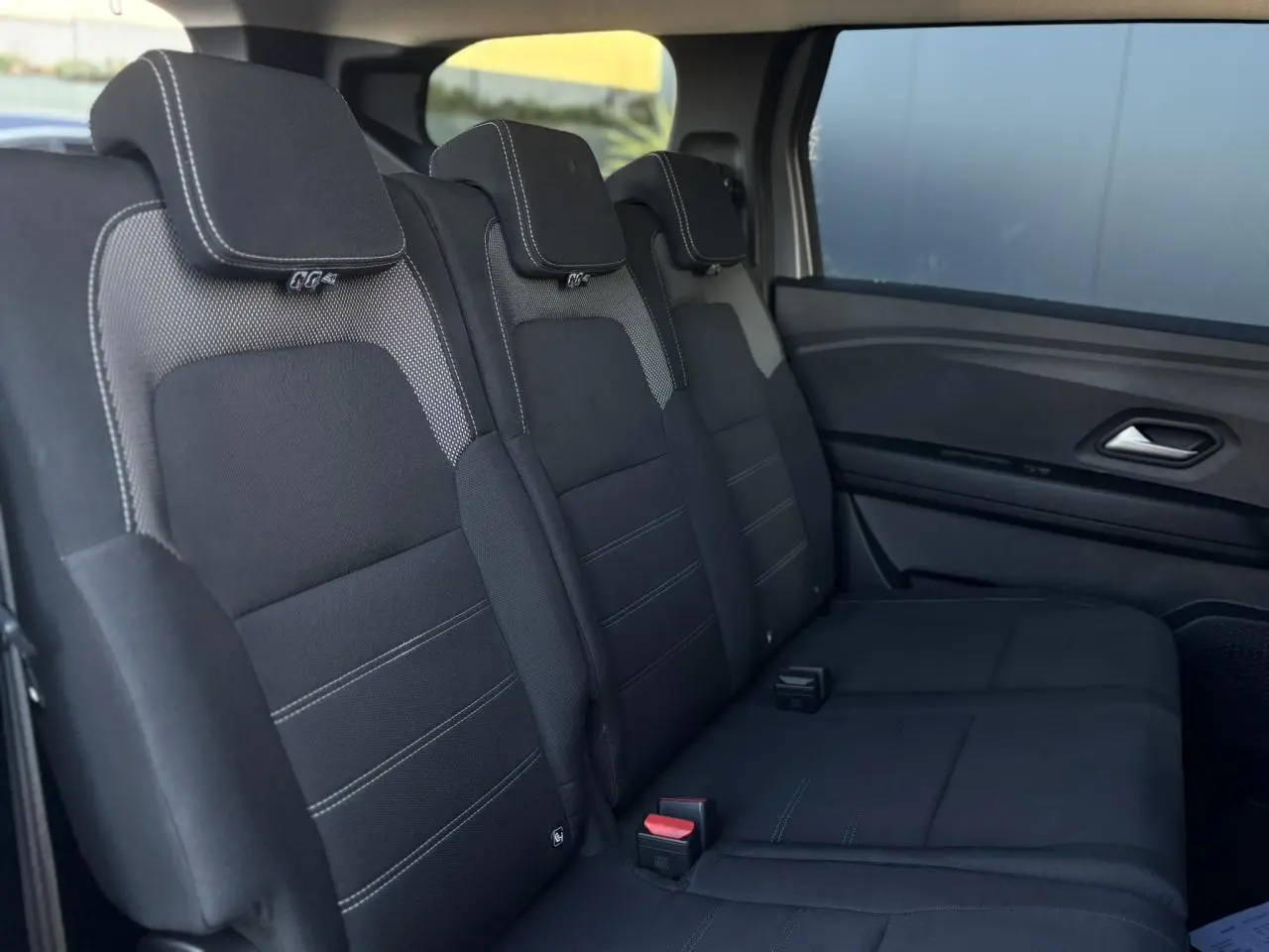 Vue latérale droite des sièges arrière noirs avec surpiqûres blanches du Dacia Jogger 2025, version Expression.