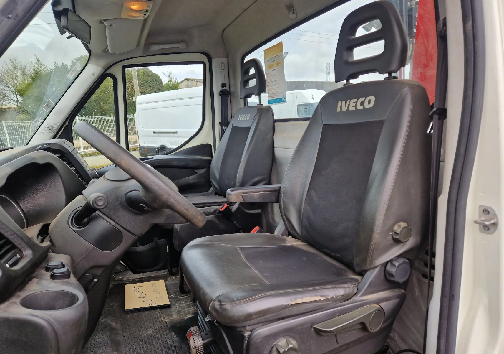 Vue intérieure côté conducteur de l'Iveco Daily Chassis Cabine 35C14 blanc, montrant les sièges en cuir avec logo Iveco.