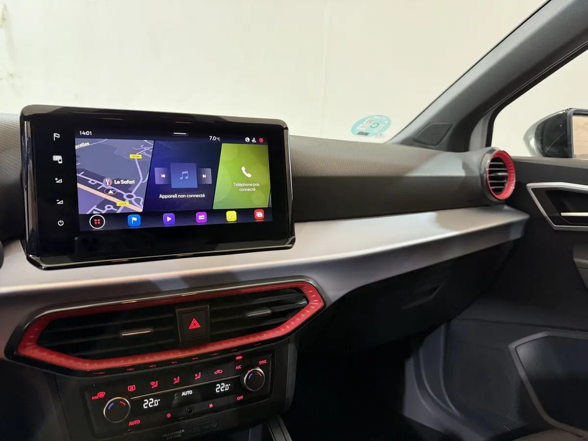 Vue intérieure côté passager du tableau de bord de la SEAT Ibiza blanc, avec écran tactile et aérateurs rouges.