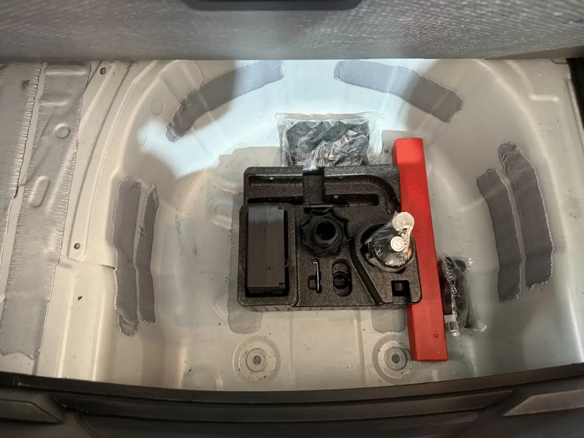 Vue plongeante sur le compartiment de rangement sous le coffre d'une SEAT Ibiza blanc, avec kit de réparation pneus.