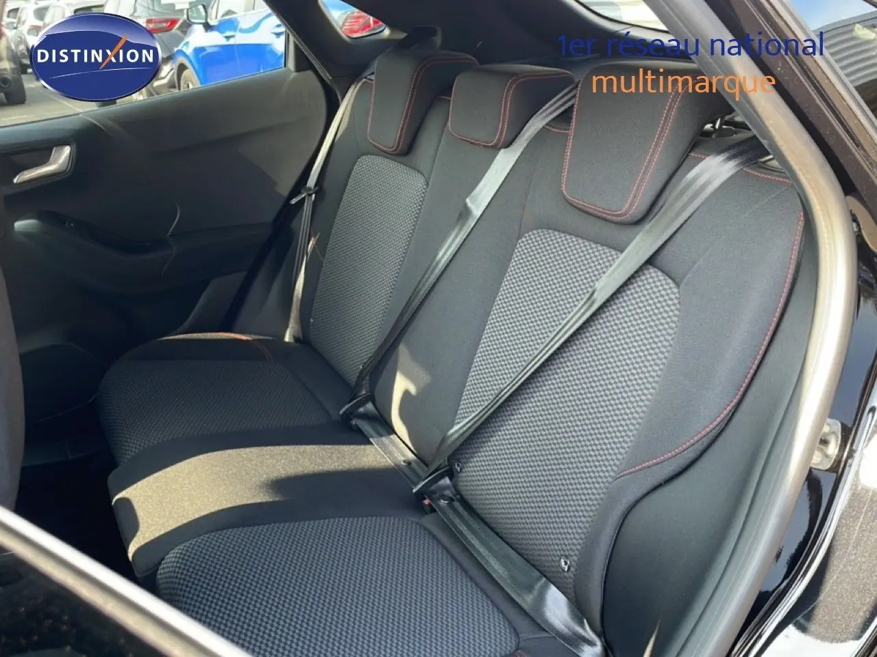 Vue intérieure côté arrière droit du Ford Puma noir agate métal, mettant en valeur les sièges arrière en tissu noir avec surpiqûres rouges.