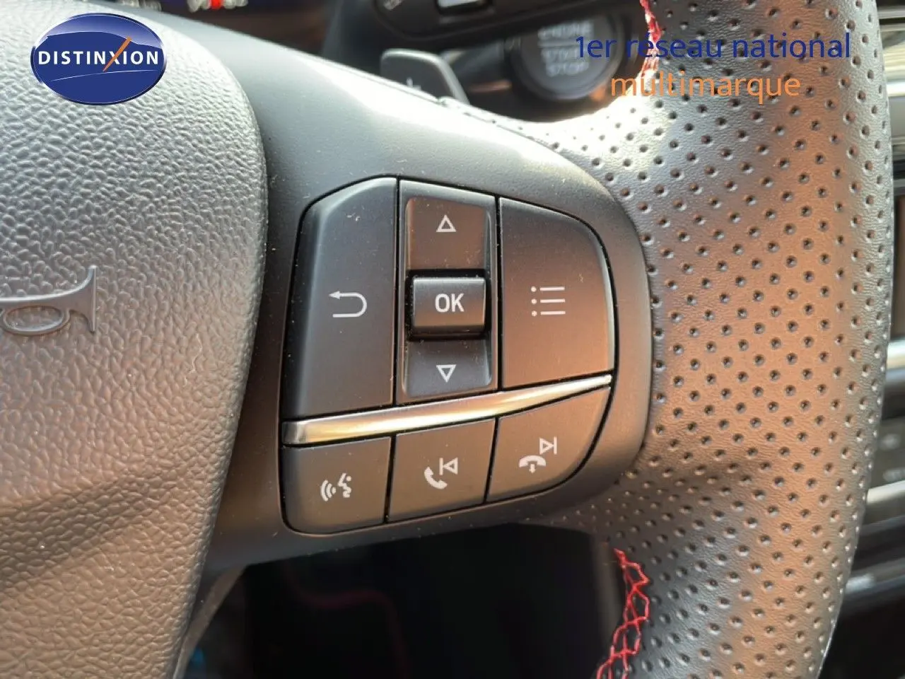 Gros plan sur les commandes multifonctions à gauche du volant perforé noir du Ford Puma 2023 finition ST-LINE.