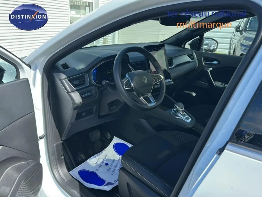 Intérieur avant gauche du Renault Symbioz blanc 2025, volant multifonction et écran tactile central visible.