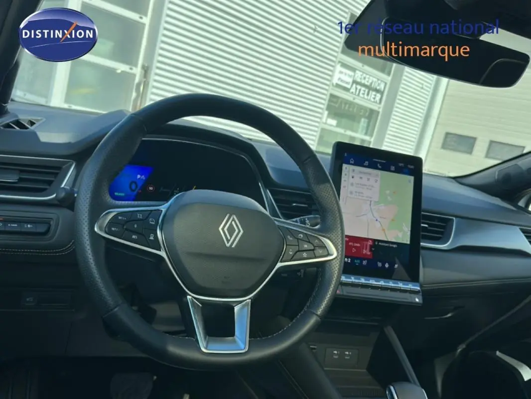 Vue intérieure centrée sur le volant noir de la Renault SYMBIOZ blanc, avec écran tactile vertical et tableau de bord numérique.