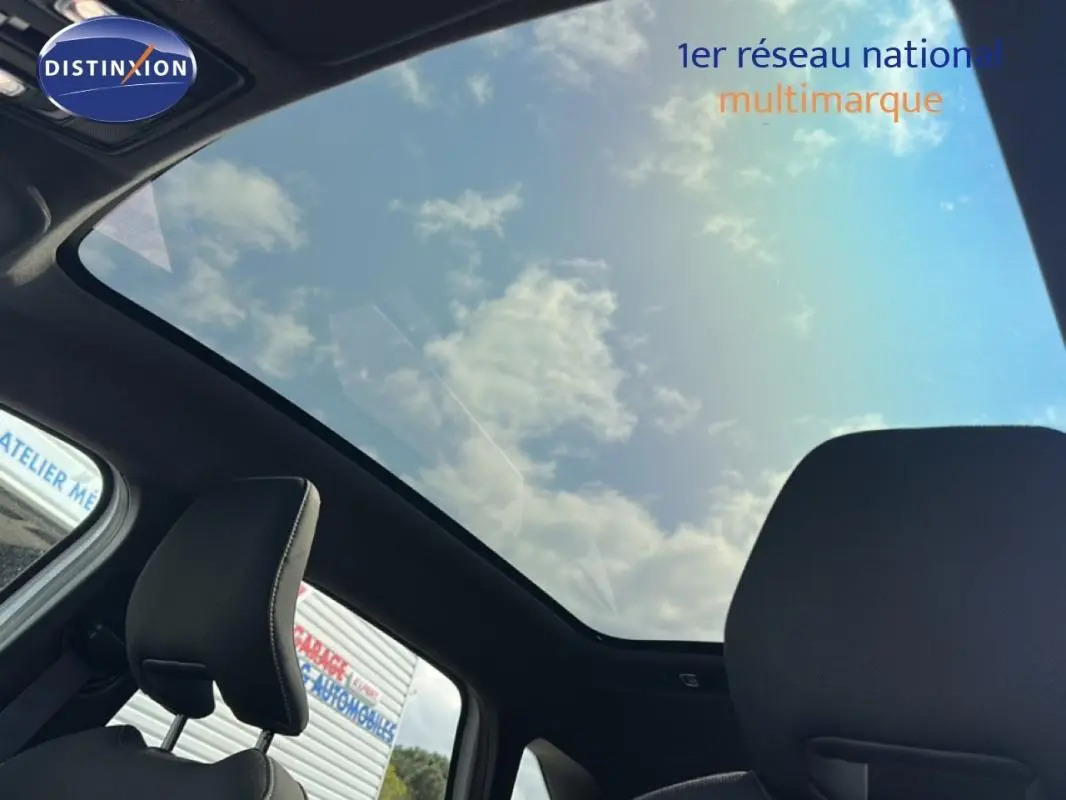 Vue intérieure du toit panoramique et des appuis-tête noirs du Renault Symbioz blanc, avec ciel nuageux visible.