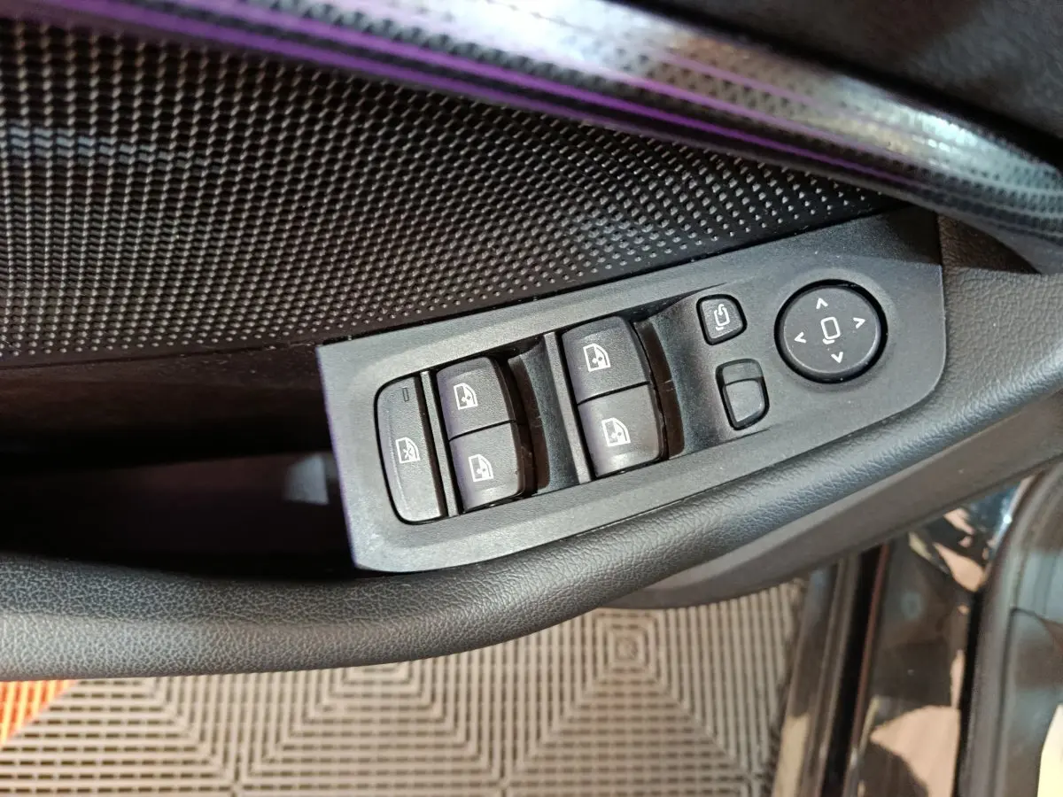 Gros plan sur les commandes de lève-vitres et rétroviseurs côté conducteur d’une BMW Série 1 noire 118i Edition Sport.