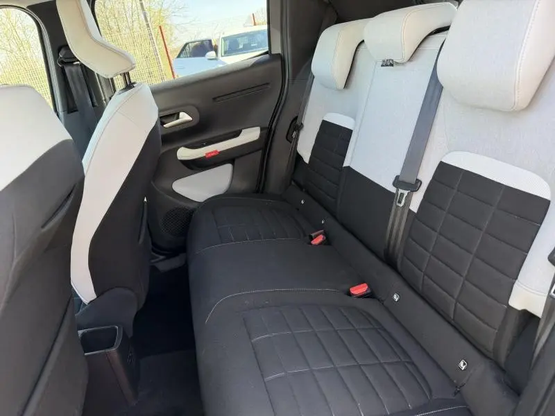 Vue intérieure arrière de la Citroën C3 2025, sièges bicolores noirs et gris avec ceinture centrale visible.