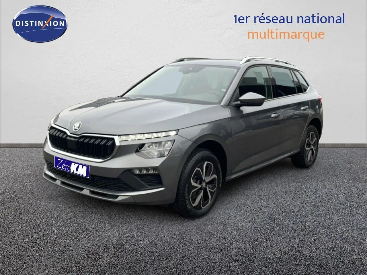 Vue 3/4 avant d'un Skoda Kamiq gris graphite 2025 avec jantes bi-ton et calandre noire distinctive.