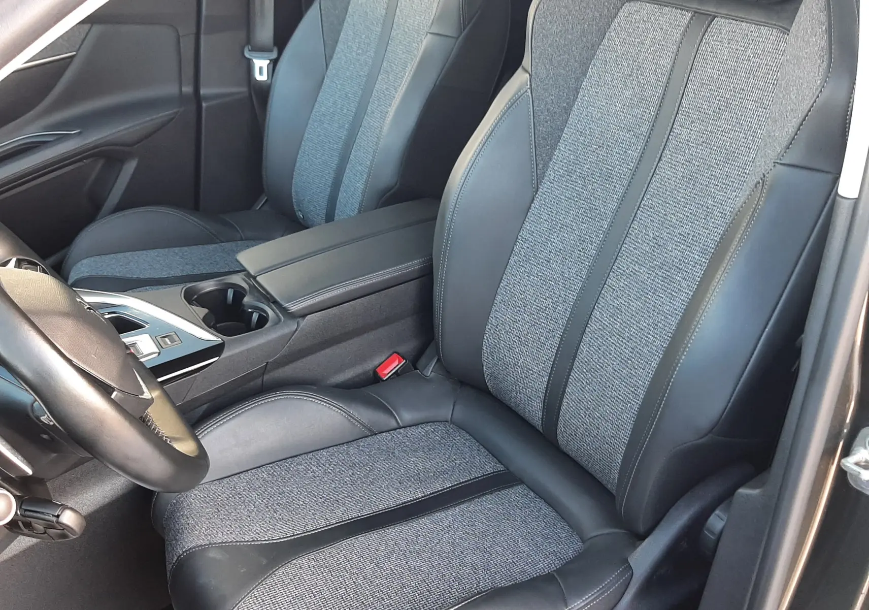Vue intérieure côté conducteur du Peugeot 3008 2019, sièges tissu gris et cuir noir avec console centrale visible.