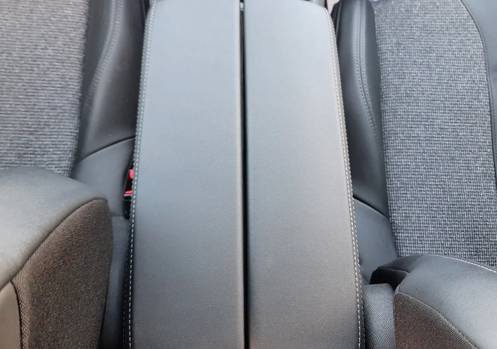 Gros plan sur l'accoudoir central noir entre les sièges avant en tissu gris du Peugeot 3008 1.5 BlueHDi 2019.