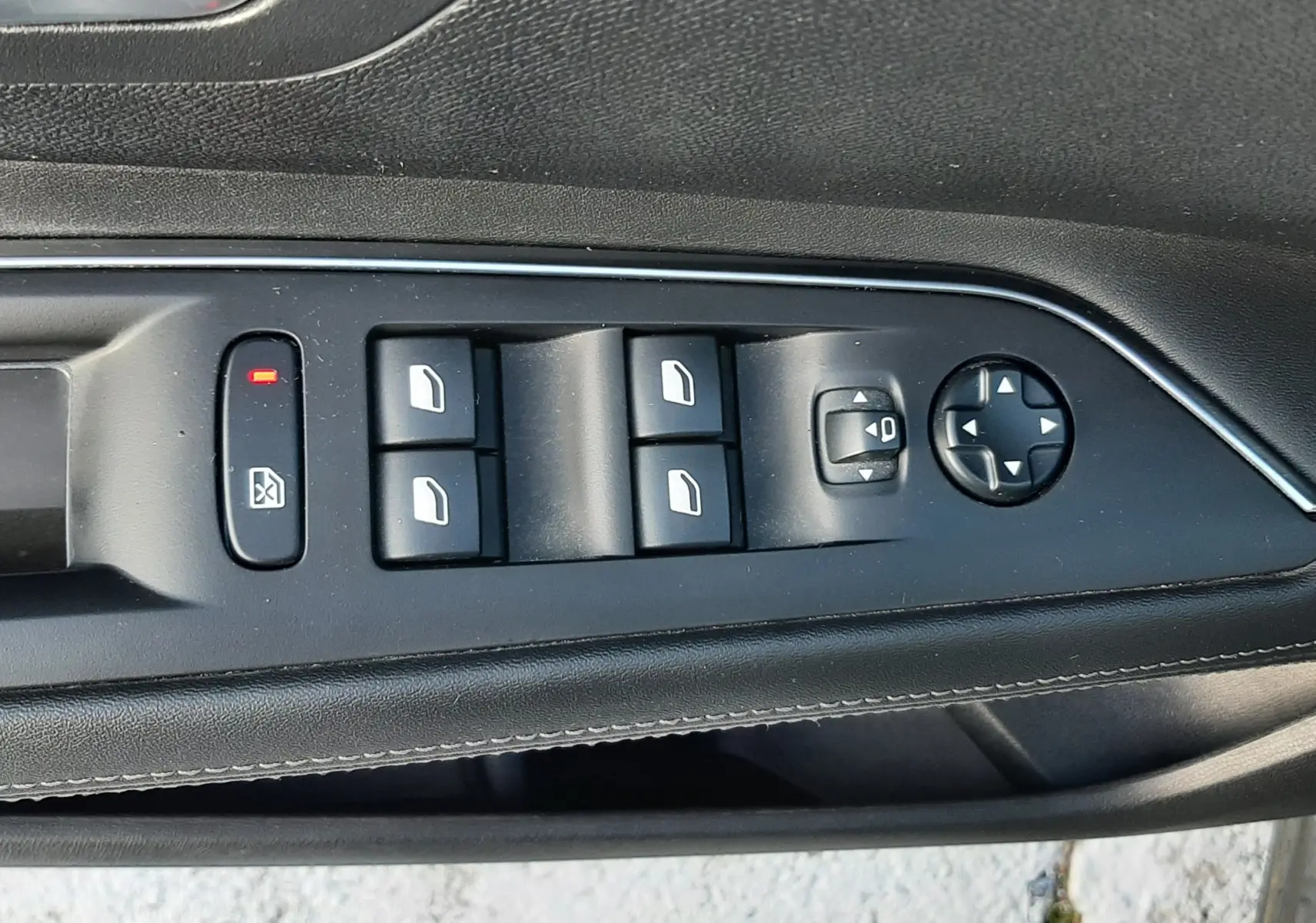 Gros plan sur les commandes de lève-vitres et réglages des rétroviseurs côté conducteur d'un Peugeot 3008 gris Amazonite.