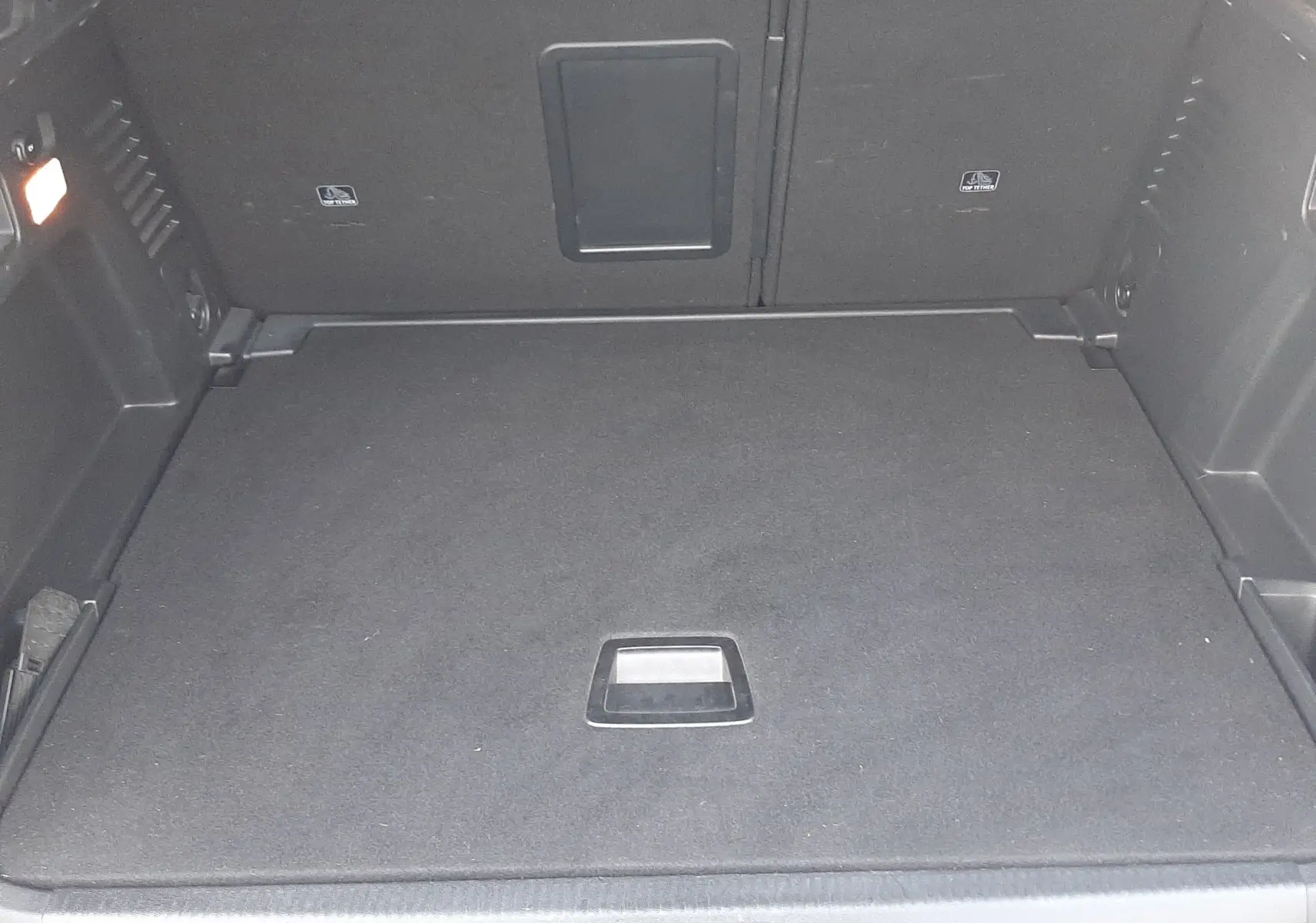 Coffre vu de l'arrière d'un Peugeot 3008 gris Amazonite, espace de chargement propre et bien aménagé.