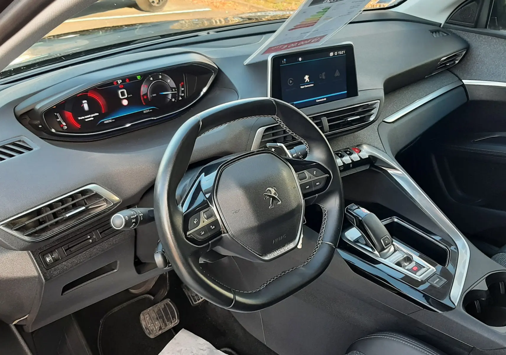 Vue intérieure côté conducteur du Peugeot 3008 gris Amazonite, mettant en valeur le volant compact, l'écran tactile central et la console moderne.