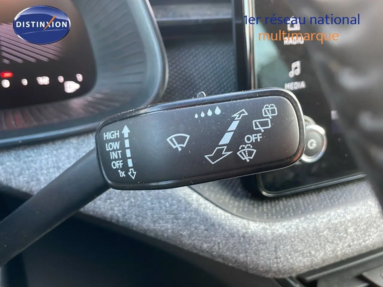 Gros plan sur la commande d’essuie-glace du Skoda Kamiq 2024, intérieur avec tableau de bord et écran tactile en arrière-plan.