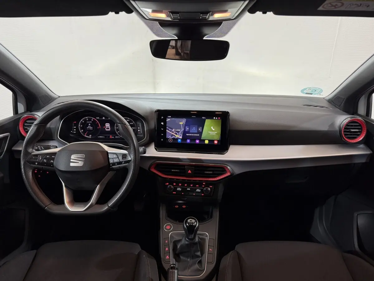 Vue intérieure frontale du tableau de bord de la SEAT Ibiza blanc avec volant cuir alu et écran tactile central.