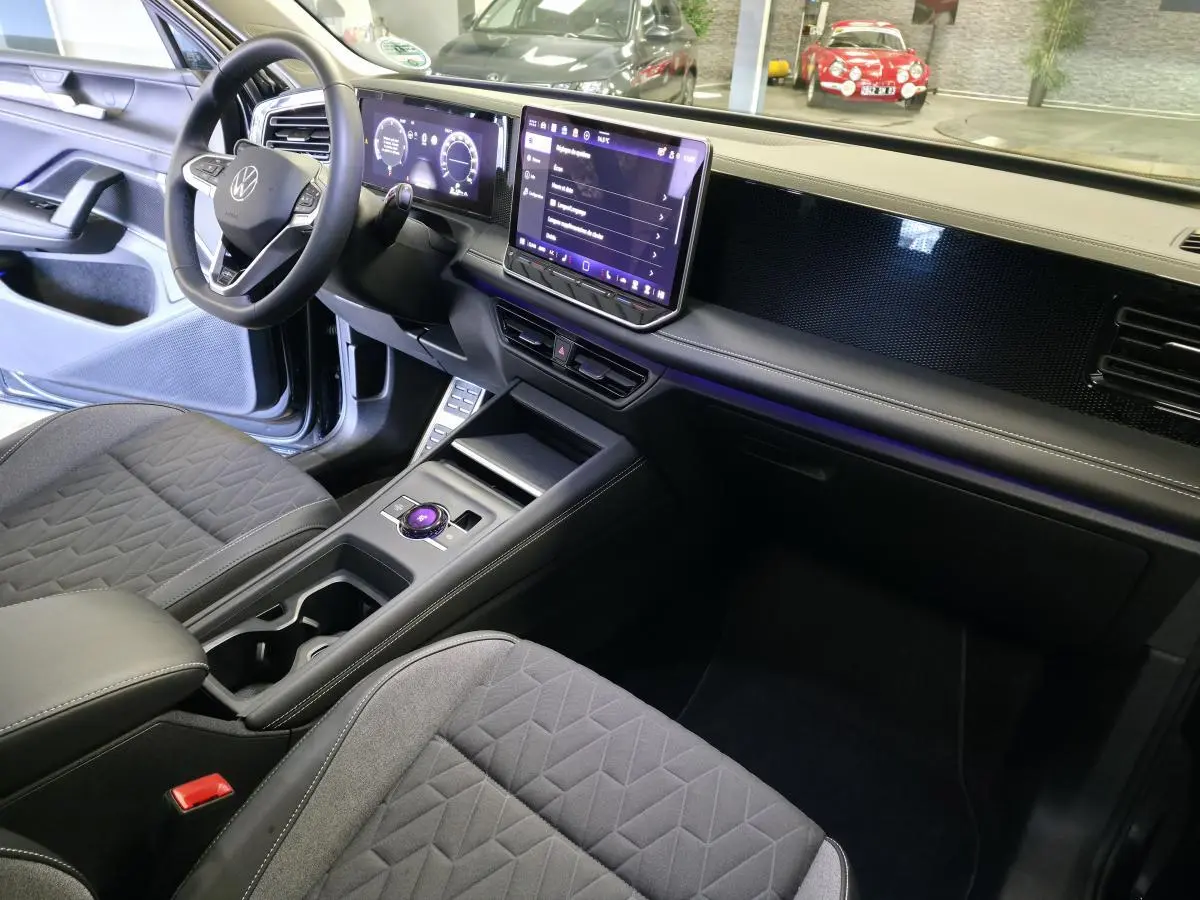 Intérieur avant droit du Volkswagen Tiguan 2025 noir, tableau de bord numérique et écran tactile central lumineux.