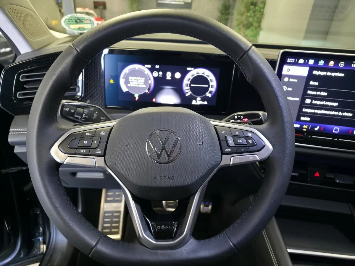 Vue rapprochée du volant en cuir noir du Volkswagen Tiguan 2025 avec tableau de bord numérique et écran tactile.