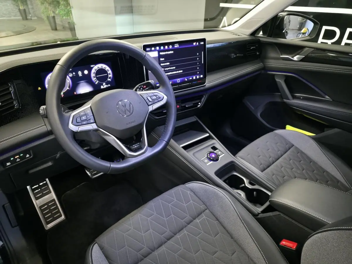 Vue intérieure côté conducteur du Volkswagen Tiguan 2025, tableau de bord numérique et écran tactile central visibles.