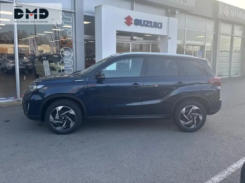 Profil côté gauche du Suzuki Vitara 2026 bleu So'Color Sphere avec jantes alu et toit noir devant concession.