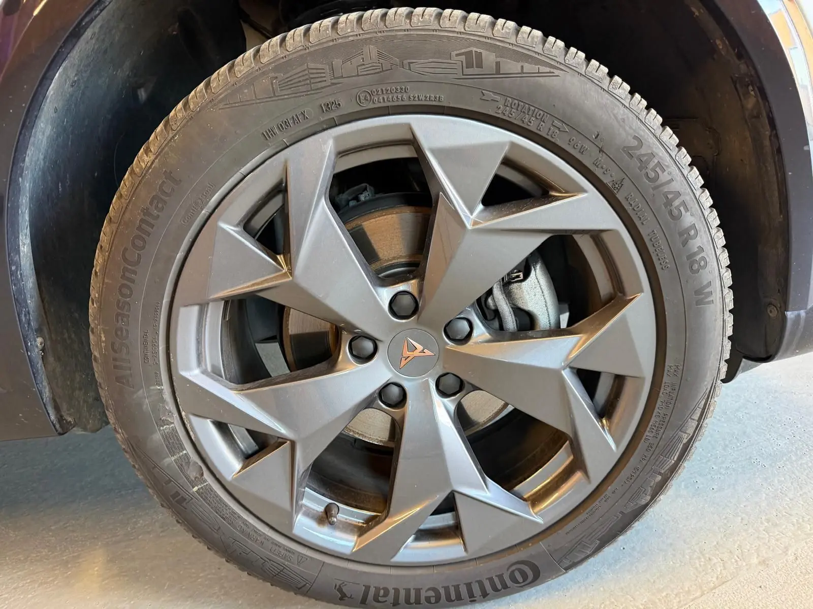 Gros plan sur la jante alliage gris anthracite avec logo CUPRA au centre, montée sur pneu Continental AllSeasonContact.
