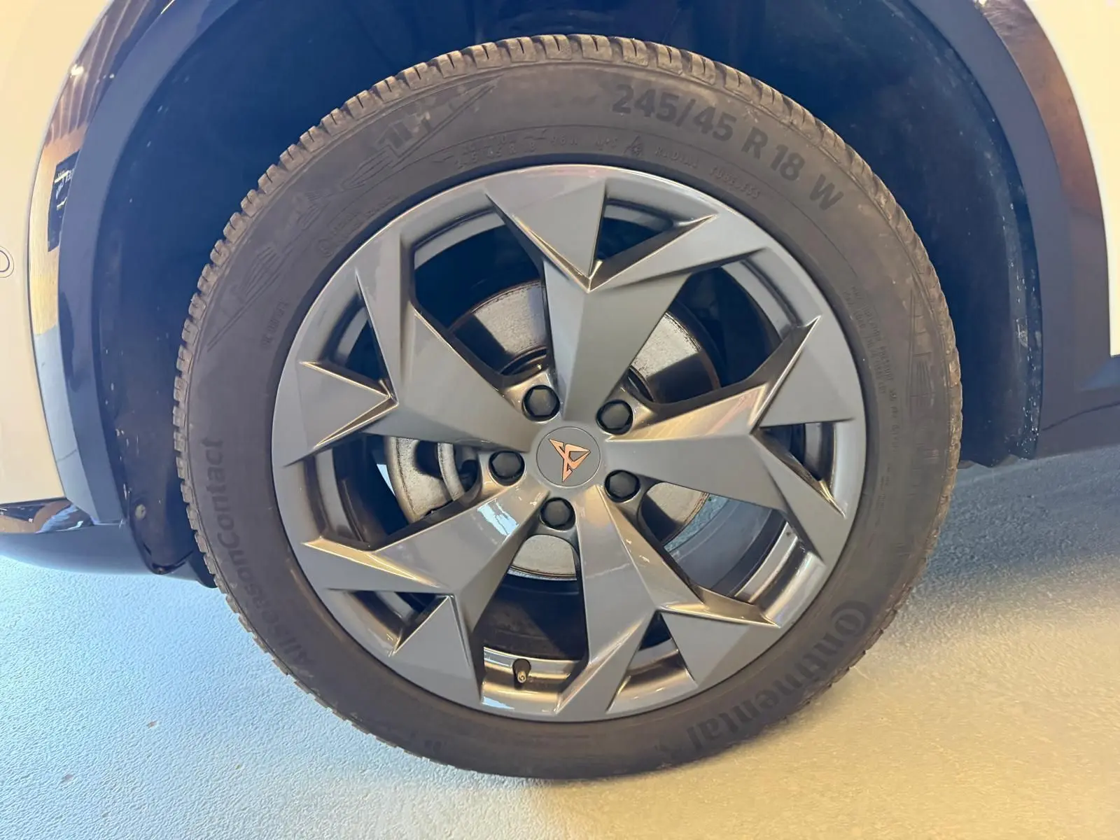 Gros plan sur la roue avant droite du CUPRA Formentor blanc, mettant en valeur la jante grise au design anguleux et le logo CUPRA central.