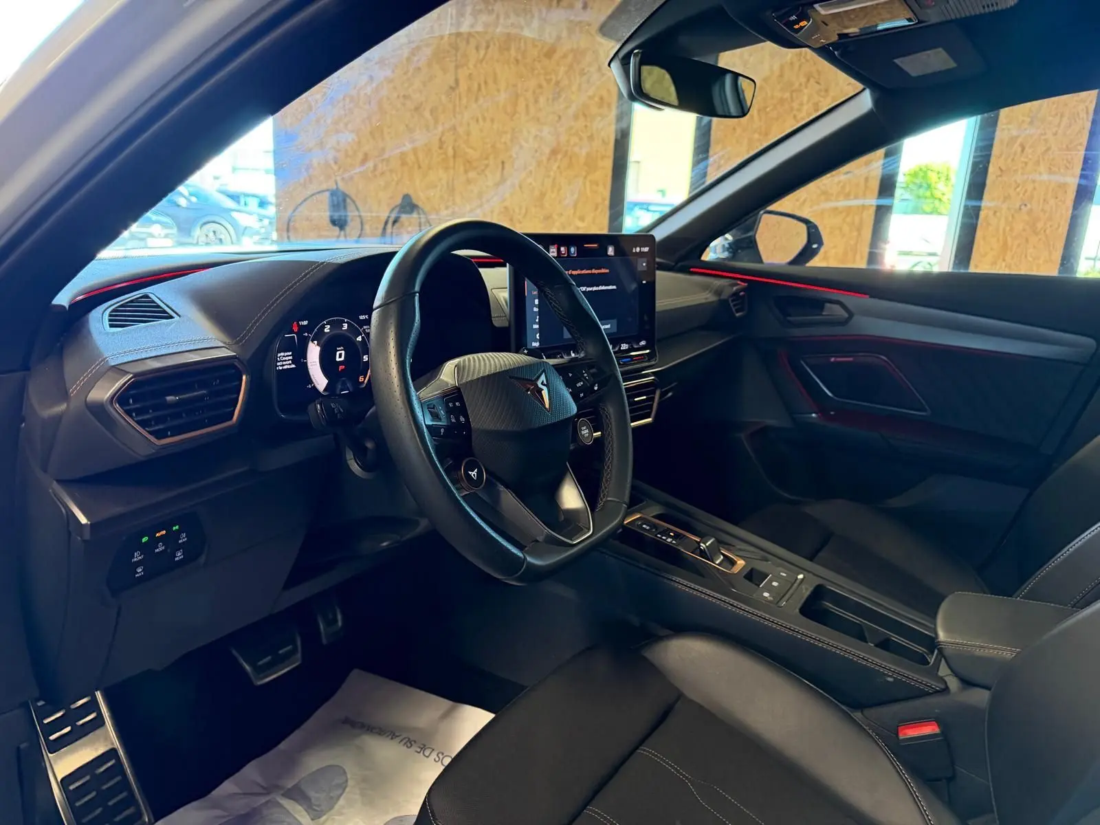 Vue intérieure côté conducteur du CUPRA Formentor 2025, avec volant cuir, écran tactile et éclairage d'ambiance rouge.