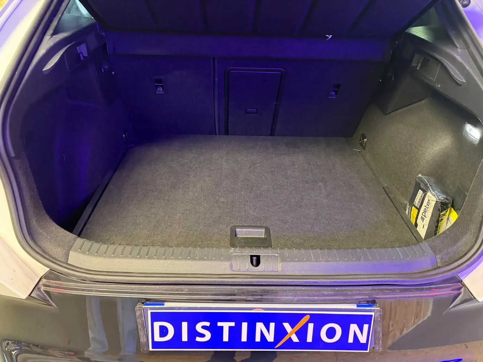 Coffre ouvert vu de l'arrière d'un CUPRA Formentor blanc 2025, avec espace de chargement propre et tapis gris.