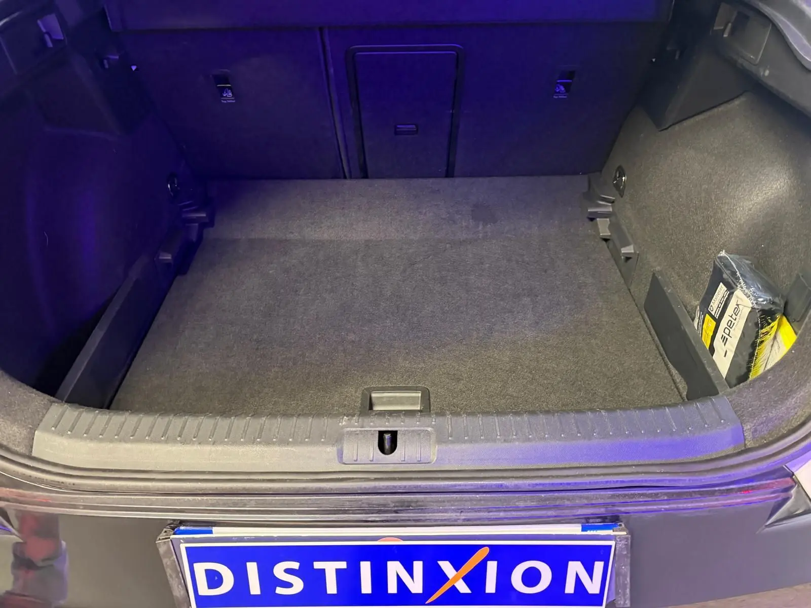 Vue du coffre ouvert d'un CUPRA Formentor blanc 2025, montrant un espace de chargement propre avec un kit de secours sur le côté droit.