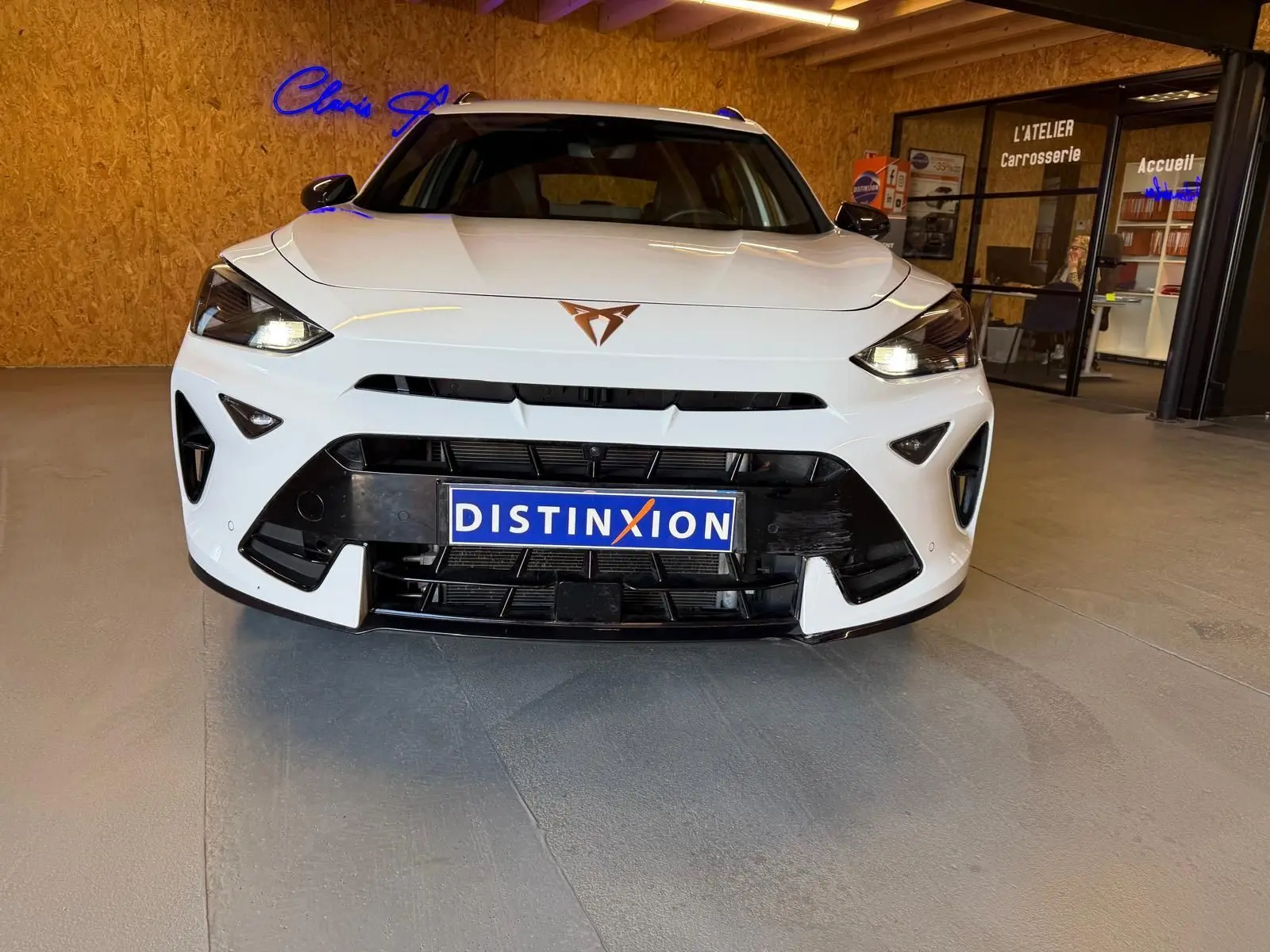 Vue frontale d’un CUPRA Formentor blanc 2025 avec logo cuivré et calandre noire dans un showroom.