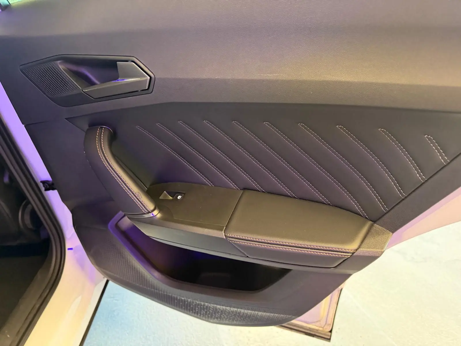 Vue rapprochée de la porte intérieure côté gauche du CUPRA Formentor blanc, avec surpiqûres apparentes et poignée en cuir.